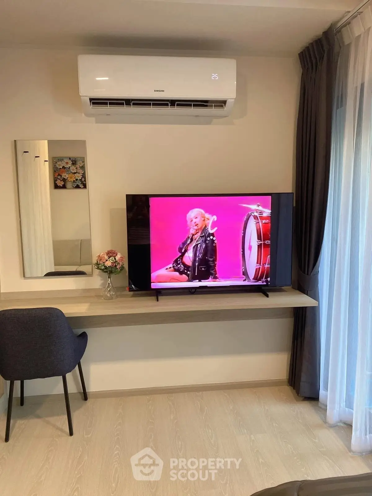 Modern living room with wall-mounted TV and air conditioning, featuring sleek furniture and decor.
