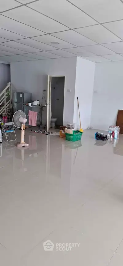 Spacious interior with tiled flooring and open layout, featuring a staircase and utility area.