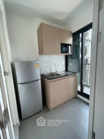 Modern compact kitchen with sleek cabinetry and balcony access