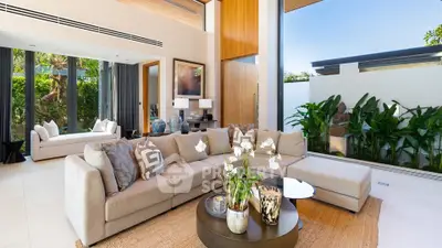 Luxurious modern living room with large windows, stylish decor, and garden view.