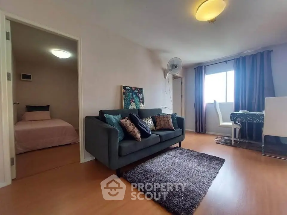Cozy living room with modern decor and adjacent bedroom, featuring stylish furniture and natural light.