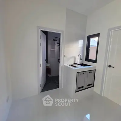 Modern minimalist kitchen with sleek design and adjacent bathroom