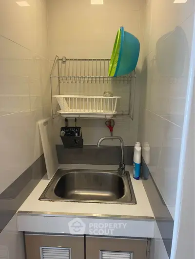 Compact kitchen sink area with dish rack and storage cabinets