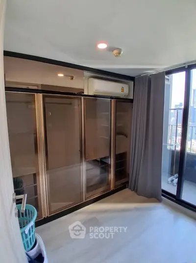 Modern bedroom with glass wardrobe and balcony view in urban apartment
