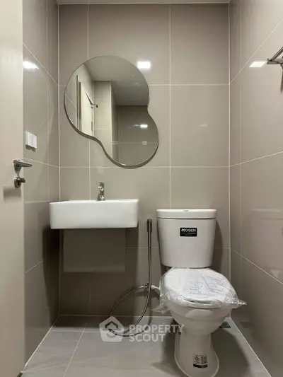 Modern bathroom with unique mirror and sleek fixtures in a contemporary apartment.