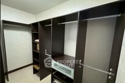 Spacious walk-in closet with dark wood shelving and ample storage space.