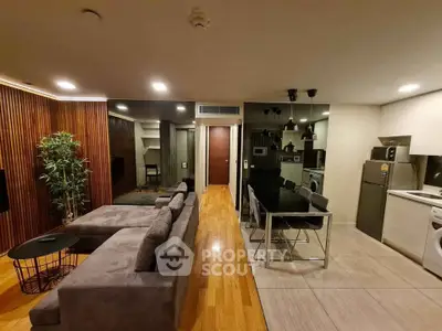 Modern open-layout living room with sleek kitchen, stylish decor, and cozy seating area.