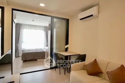 Modern apartment interior with cozy living room and bedroom separated by glass partition.