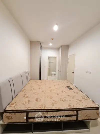 Spacious bedroom with modern design and comfortable mattress in a well-lit apartment.