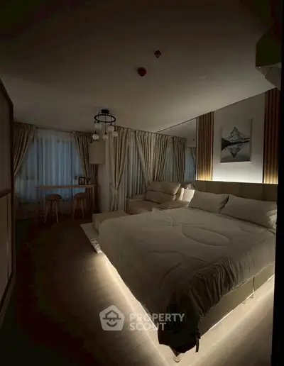 Luxurious bedroom with ambient lighting and elegant decor, featuring a cozy seating area and large windows.