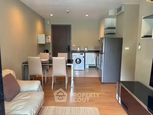 Modern living room with dining area and kitchen featuring a washing machine, ideal for urban living.