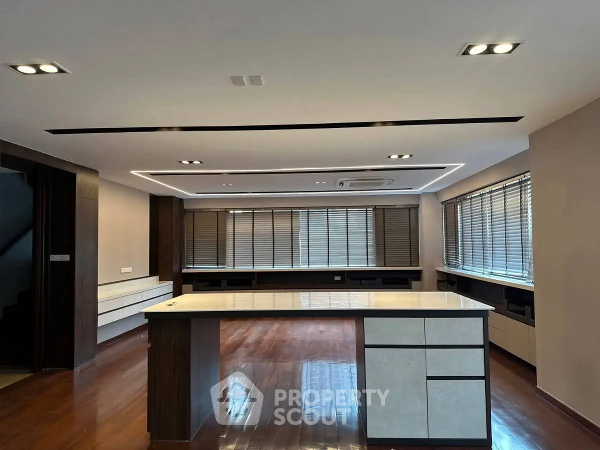 Spacious modern living room with sleek wooden flooring and large windows for natural light.