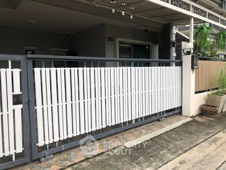 Modern residential entrance with sleek gate design and paved pathway