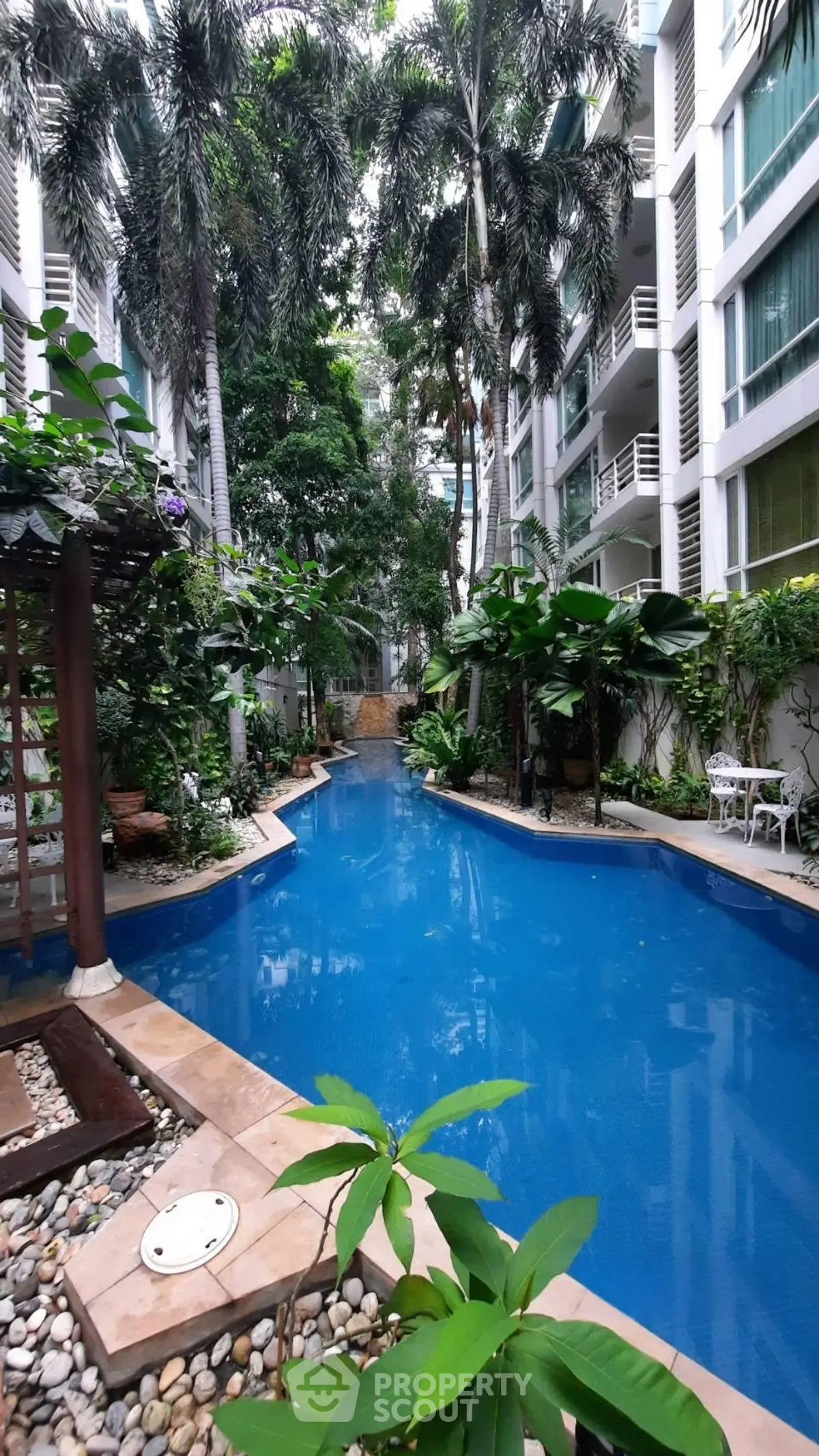 Luxurious apartment complex with tropical pool and lush greenery