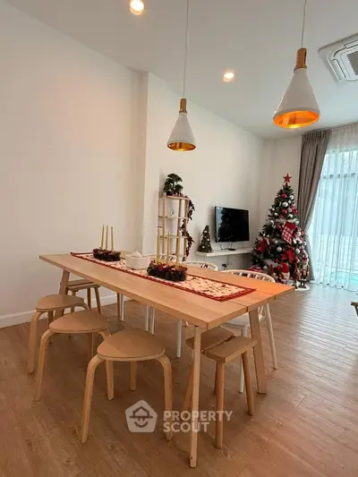Modern living room with festive decor, wooden flooring, and stylish lighting, perfect for holiday gatherings.