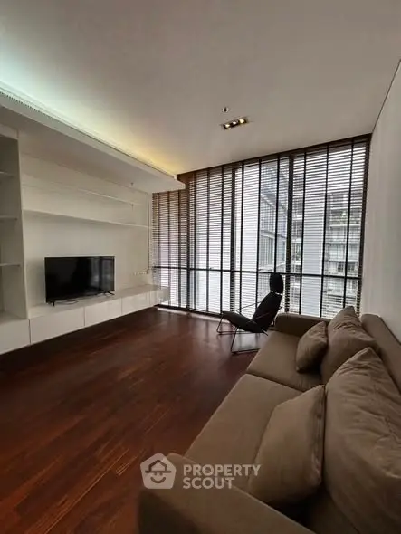 Spacious modern living room with floor-to-ceiling windows and sleek furnishings.