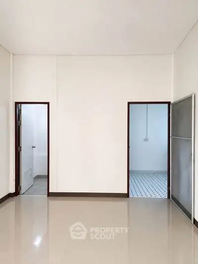 Spacious minimalist interior with tiled floor and two doorways, ideal for customization.