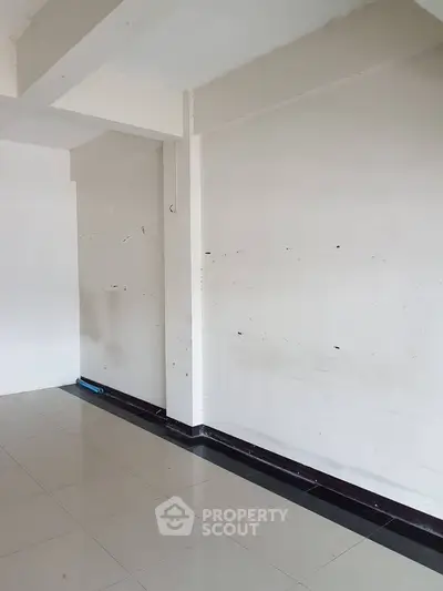 Spacious empty room with tiled flooring and white walls, ready for customization.