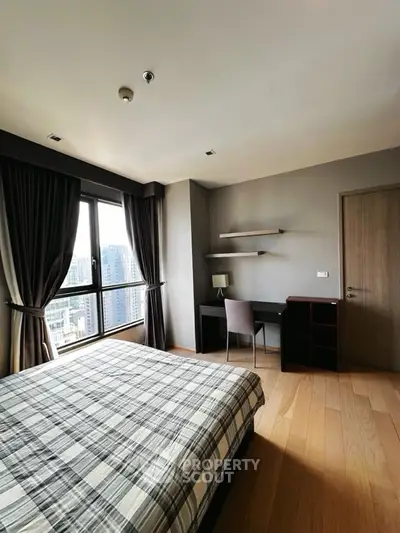 Modern bedroom with city view, featuring a cozy bed, study desk, and large windows for natural light.