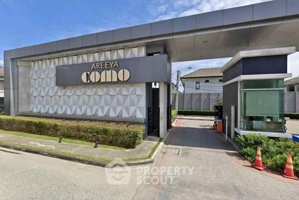 Modern gated community entrance with stylish design and lush landscaping.