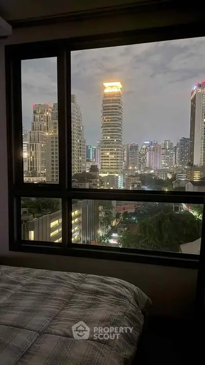 Stunning cityscape view from a high-rise apartment bedroom window at night.