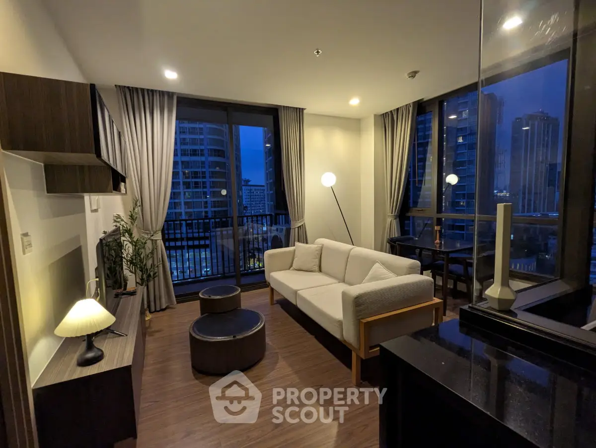 Modern living room with city view, elegant furnishings, and ambient lighting in a high-rise apartment.