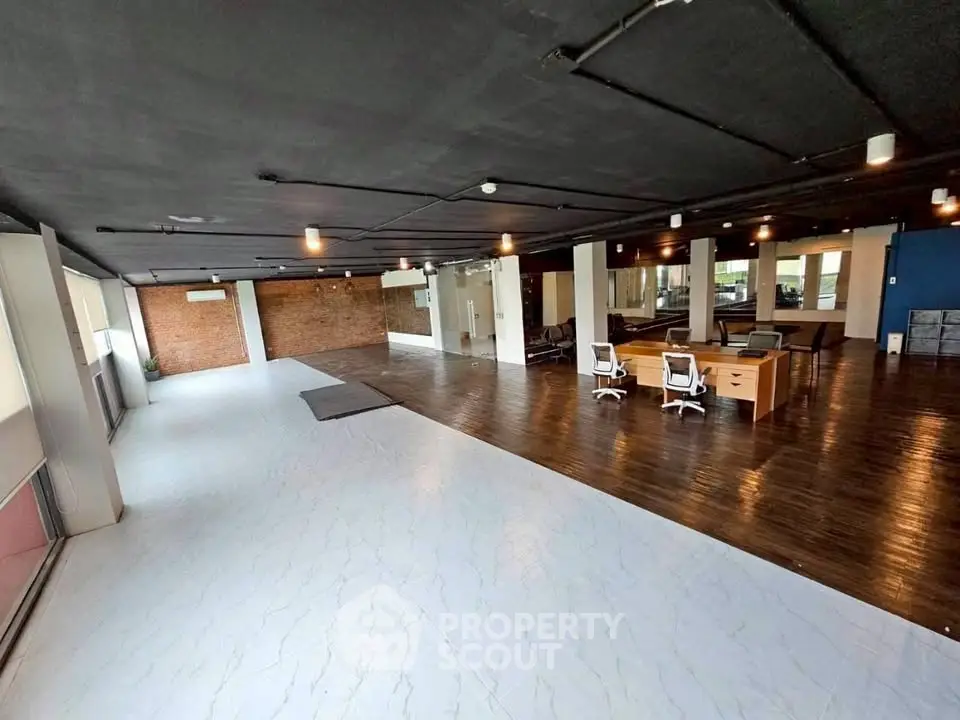Spacious open-plan office with modern design and large windows for natural light.