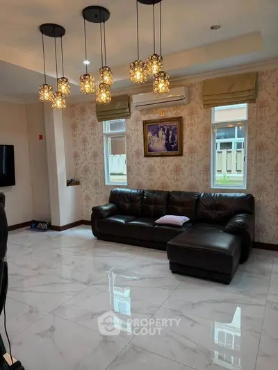 Elegant living room with modern lighting, leather sofa, and marble flooring in a stylish home.
