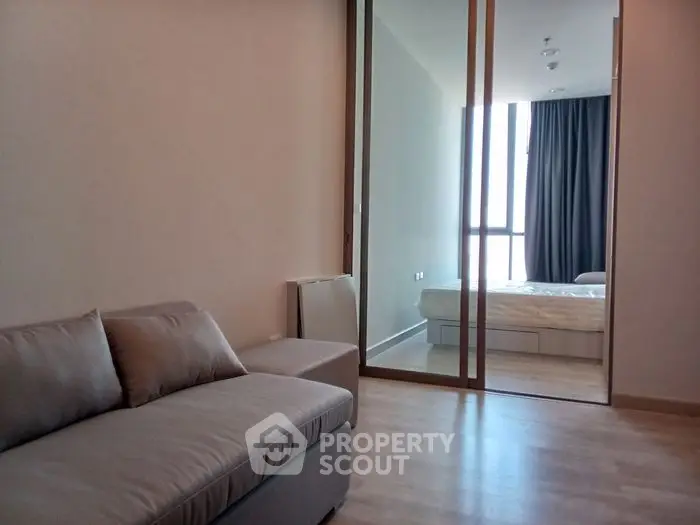 Modern apartment with cozy living room and bedroom separated by glass partition.
