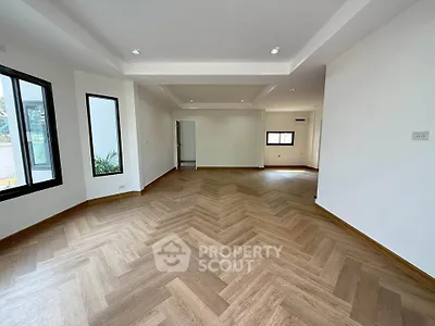 Spacious modern living room with elegant wooden flooring and ample natural light.