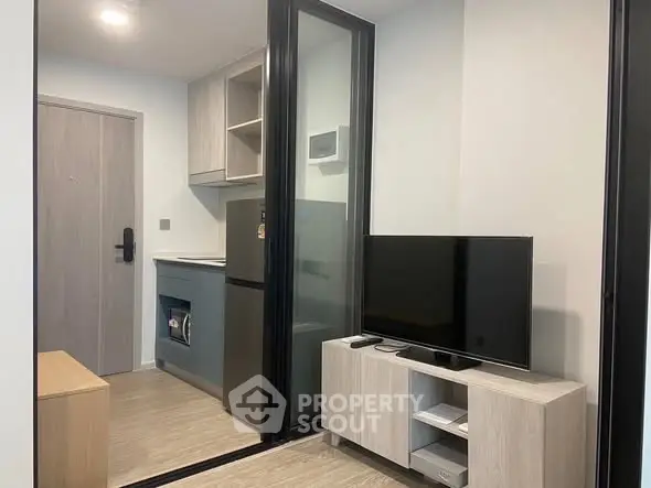 Modern compact living room with sleek TV stand and glass partition in stylish apartment.