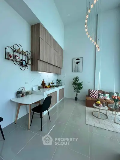 Modern living room with high ceiling, stylish decor, and open kitchen layout
