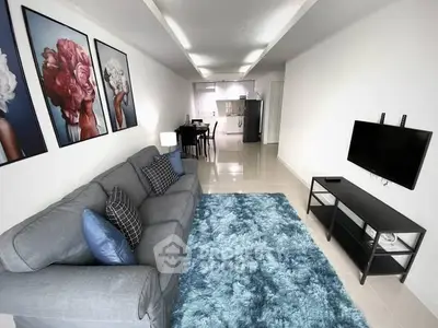 Modern living room with stylish decor and open kitchen layout, featuring a cozy sofa and vibrant artwork.