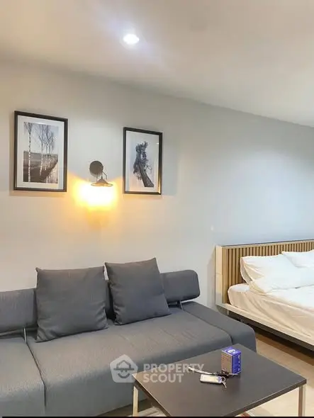 Modern living room with stylish sofa and wall art, adjacent to a cozy bedroom area.