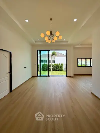 Spacious modern living room with elegant chandelier and garden view.