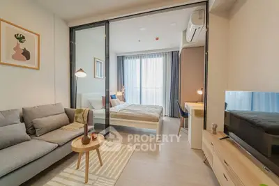 Modern studio apartment with stylish living area and cozy bedroom separated by glass doors.