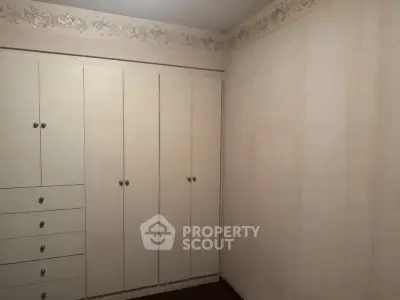 Spacious bedroom with built-in wardrobe and floral wallpaper border.