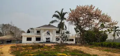 Stunning white mansion with lush garden and palm trees, perfect for luxury living.