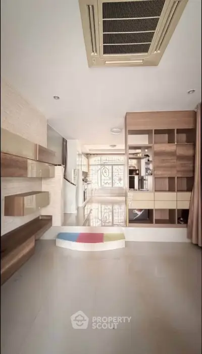 Spacious modern living room with built-in shelves and stylish ceiling air conditioning.