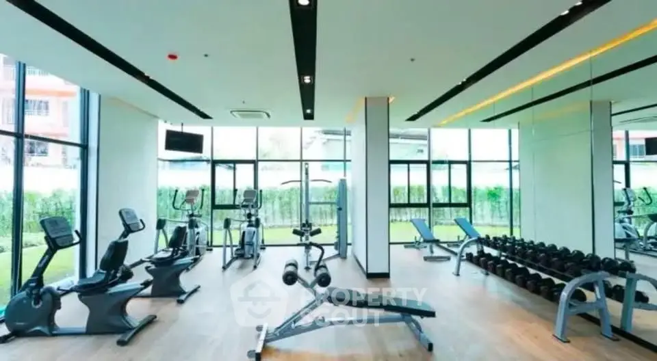 Modern gym with state-of-the-art equipment and large windows offering garden views.
