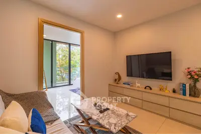 Modern living room with marble coffee table and large TV, opening to a bright balcony with greenery view.