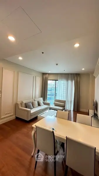 Elegant living room with cozy seating and dining area, featuring large windows and modern decor.