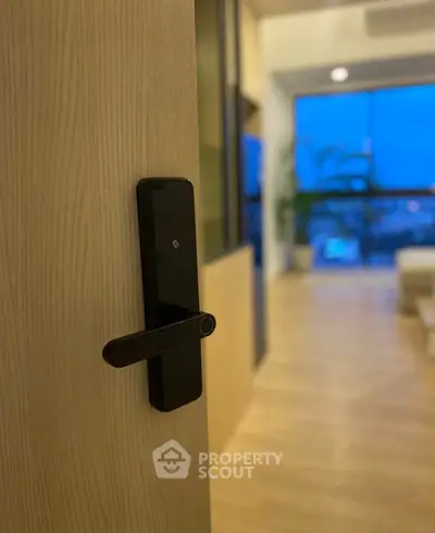 Modern apartment entrance with sleek digital lock and spacious living area view.