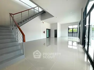 Spacious modern interior with sleek staircase and large windows, perfect for natural light and open living.