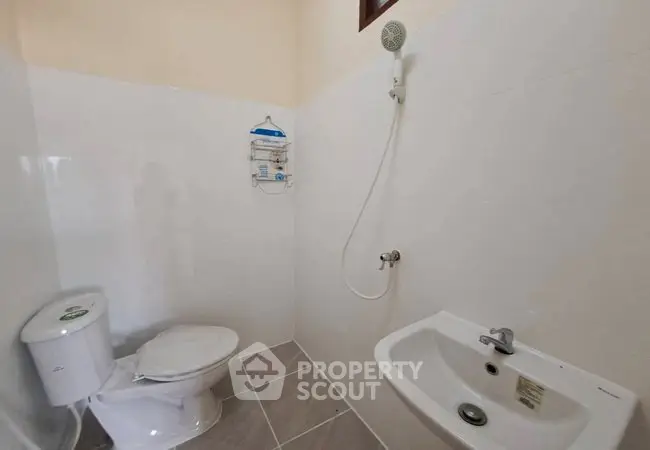 Minimalist bathroom with shower, toilet, and sink in a compact layout.