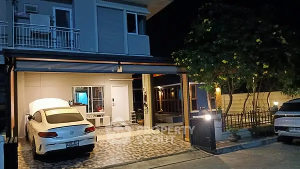 Modern house exterior with garage and parked cars at night