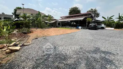 Spacious residential property with large gravel driveway and lush greenery.