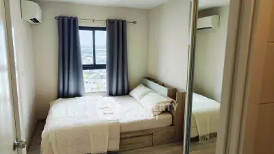 Cozy bedroom with city view, featuring modern decor and ample natural light.