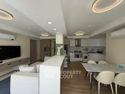 Modern open-layout living room and kitchen with stylish lighting and contemporary furniture.