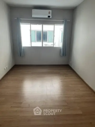 Spacious empty room with wooden flooring and air conditioning